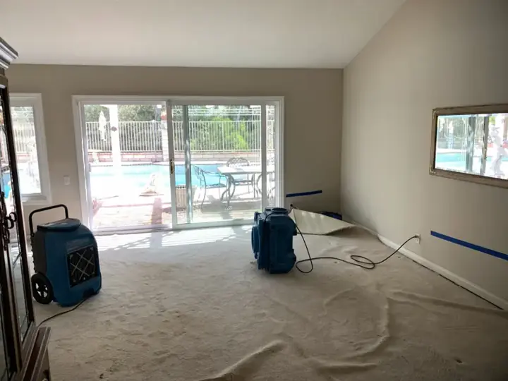 Dehumidifier and air mover drying a family room beside a backyard pool in Temecula