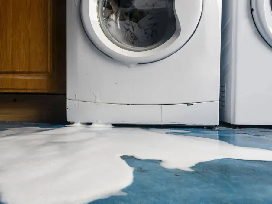 Washing machine overflow spreading across a laundry room floor