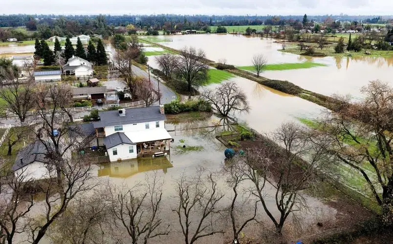 Floodwater spread across low ground and around homes beside a creek